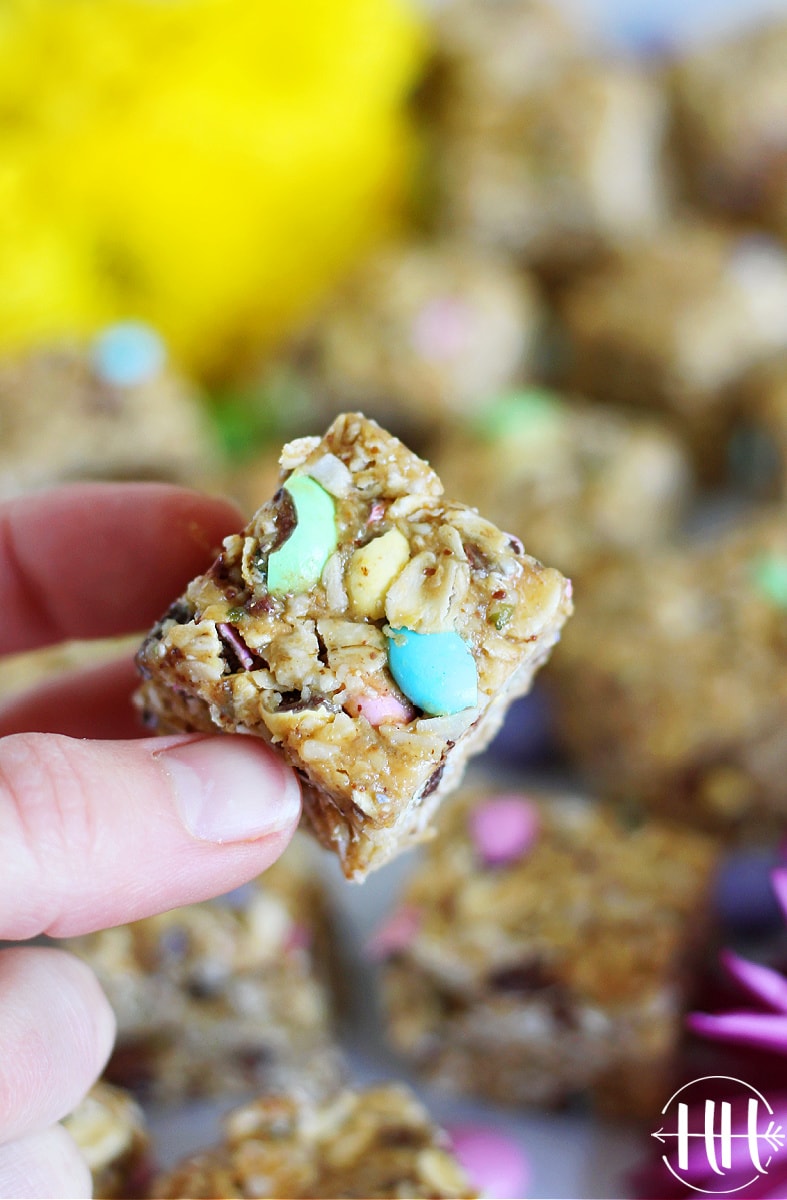 A woman's hand holding up an Easter M&M Cookie Bar with pastel M&Ms.