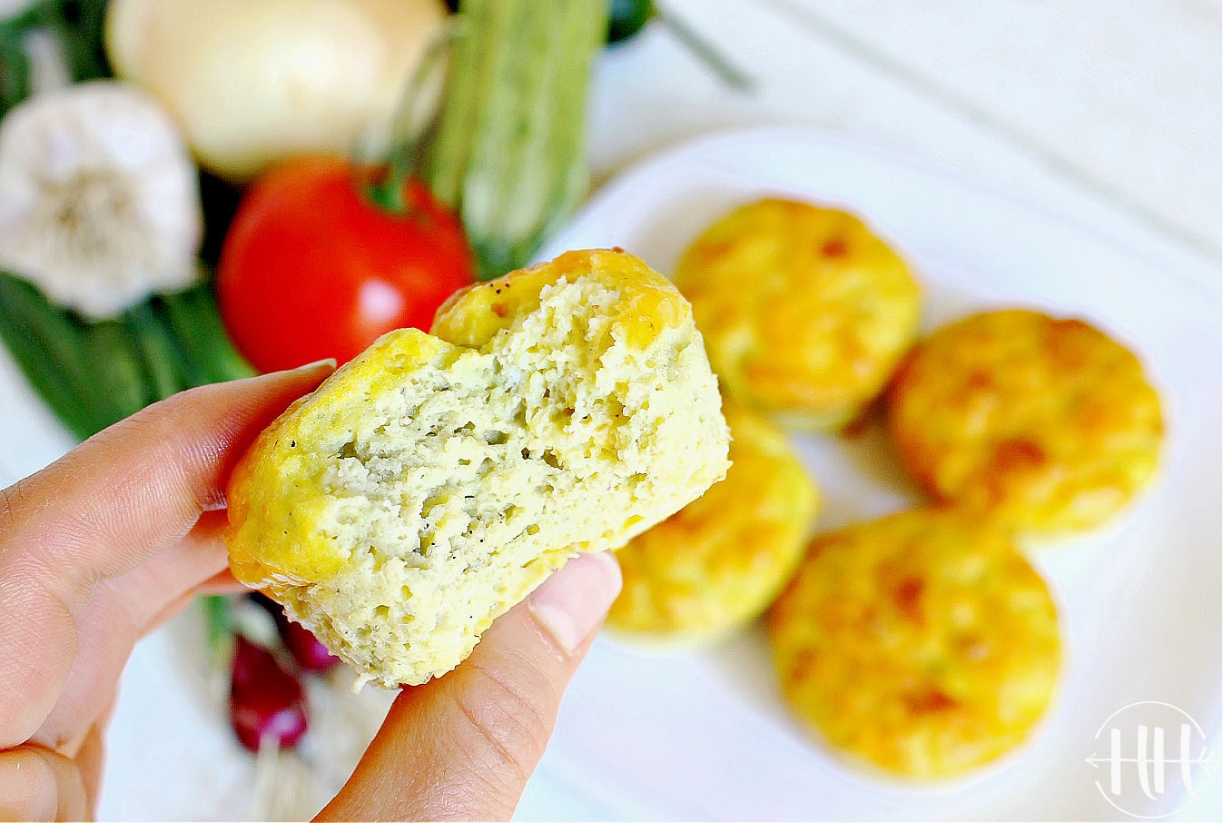 A woman's hand holding a clean eating egg muffin with a bite taken out.