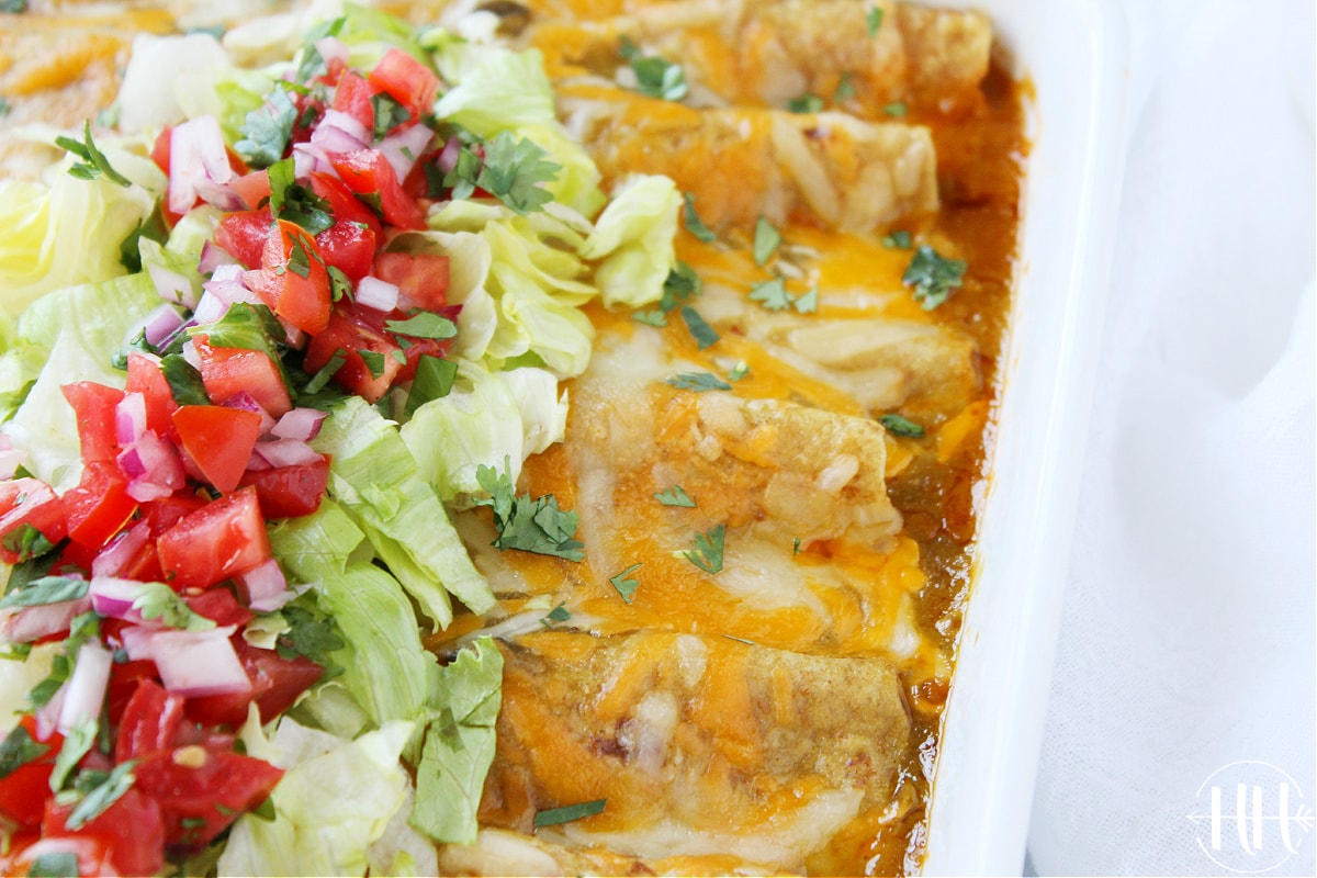 Up close photo of easy beef enchiladas in a white pan topped with lettuce.