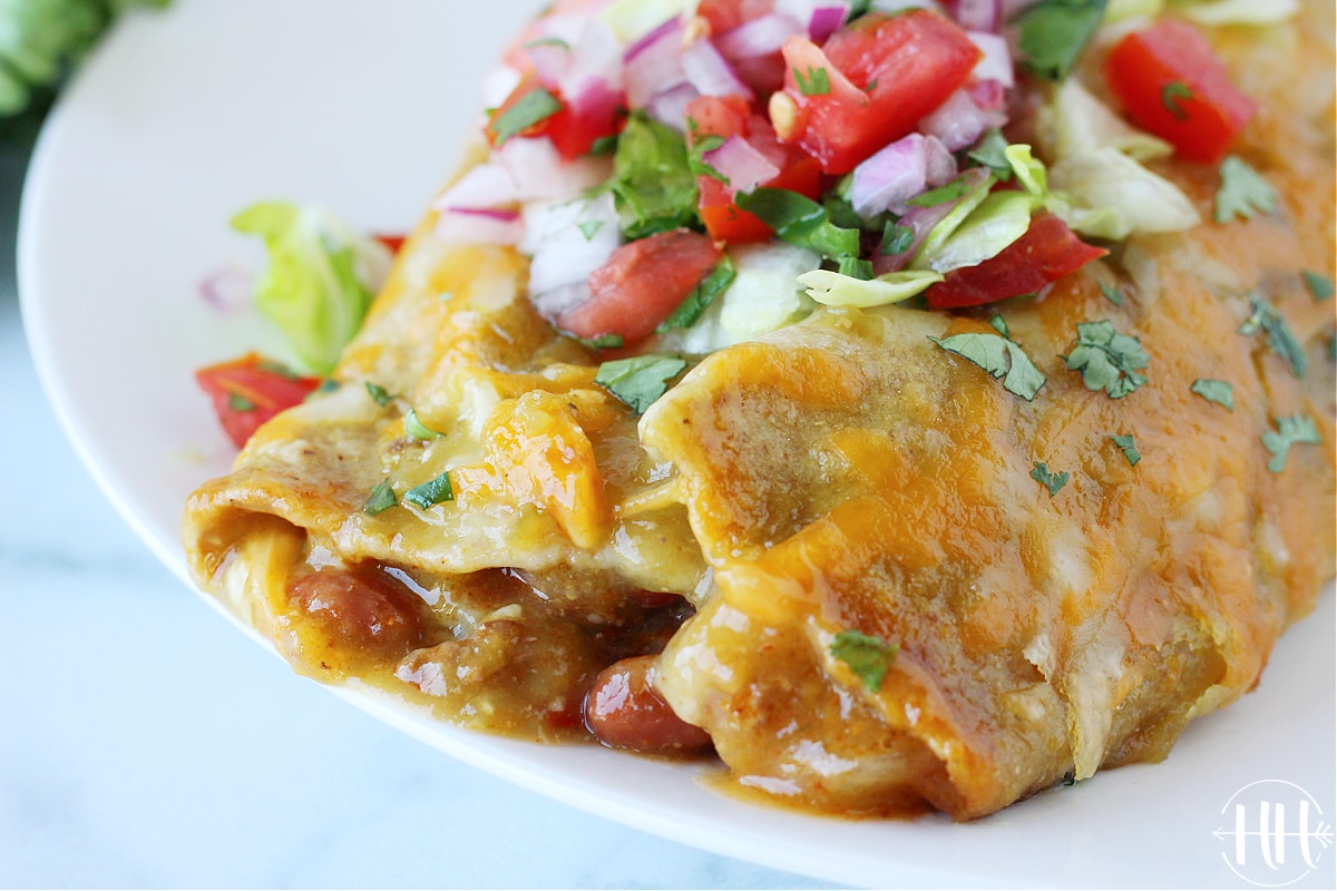 Up close photo of the end of a beef enchilada with beans and cheese.