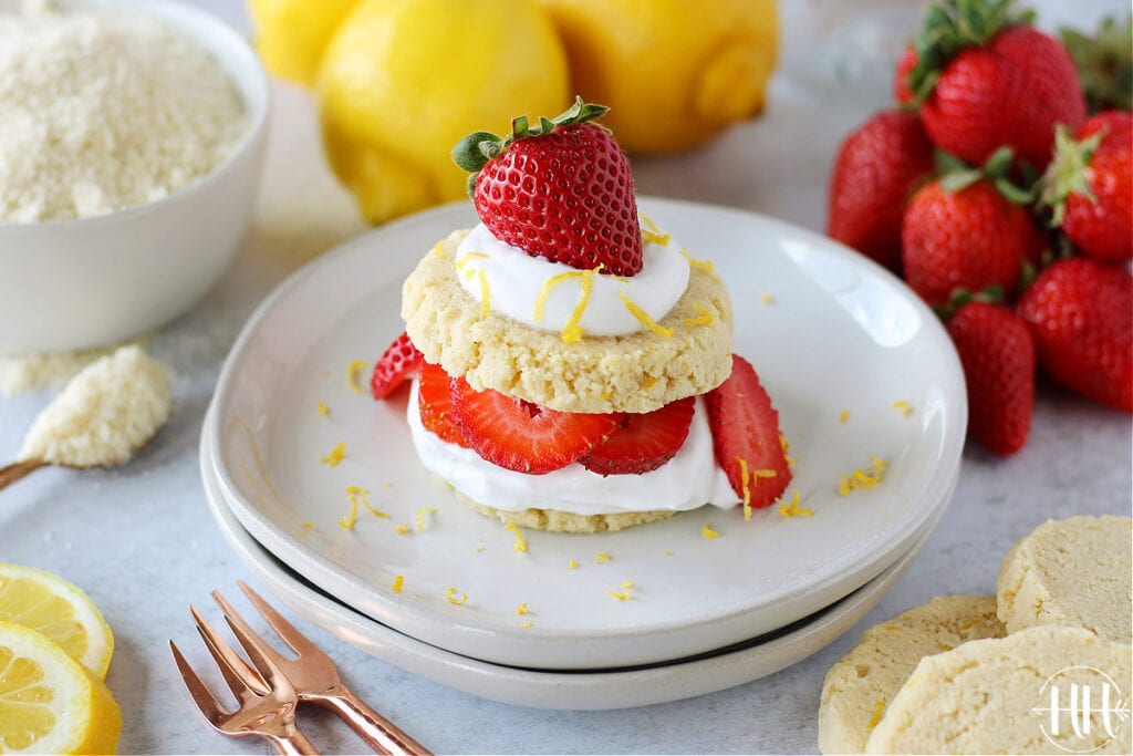 Shortcake cookies with whipped cream and strawberries surrounded by lemons and Amoretti almond flour.