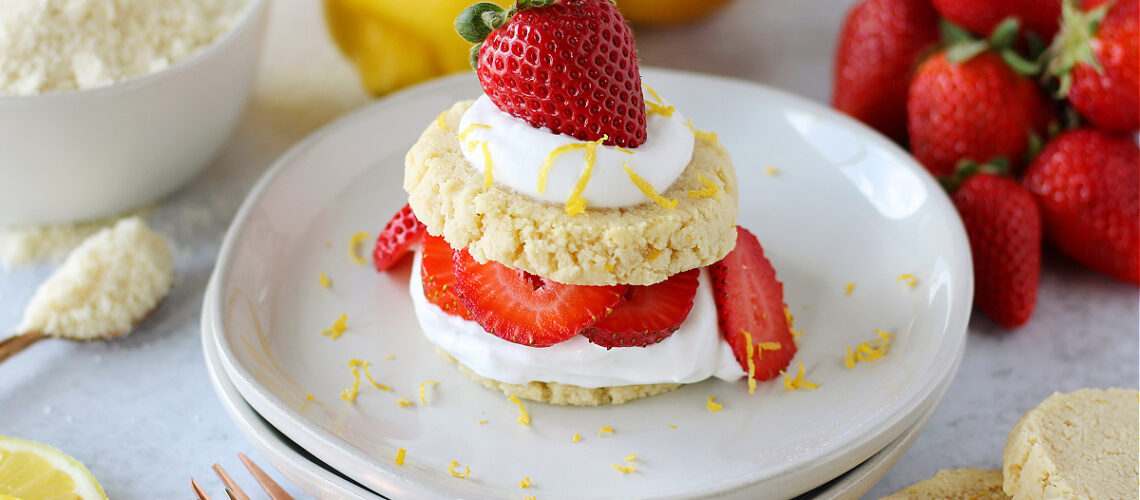 Lemon strawberry shortcake cookies with whipped cream and sliced strawberries on a white plate.
