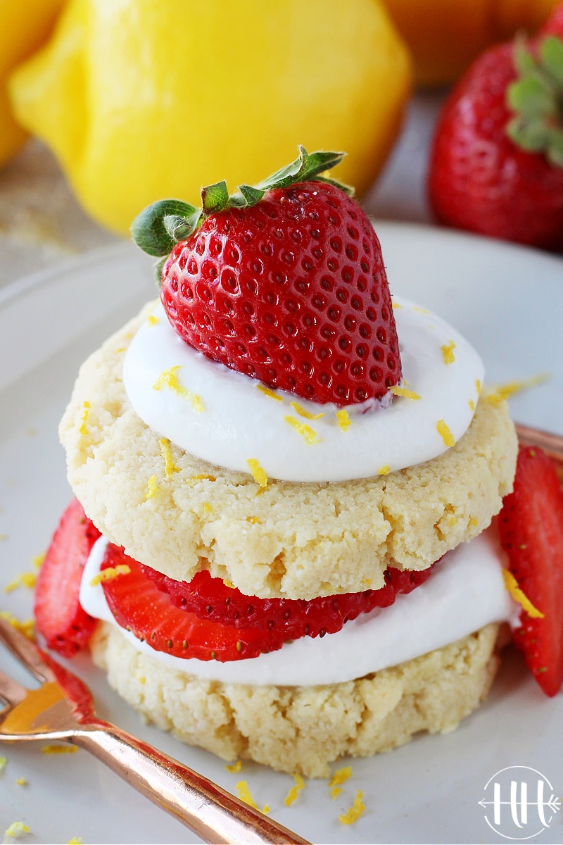 A fresh strawberry on top of whipped cream and lemon shortcake cookies.