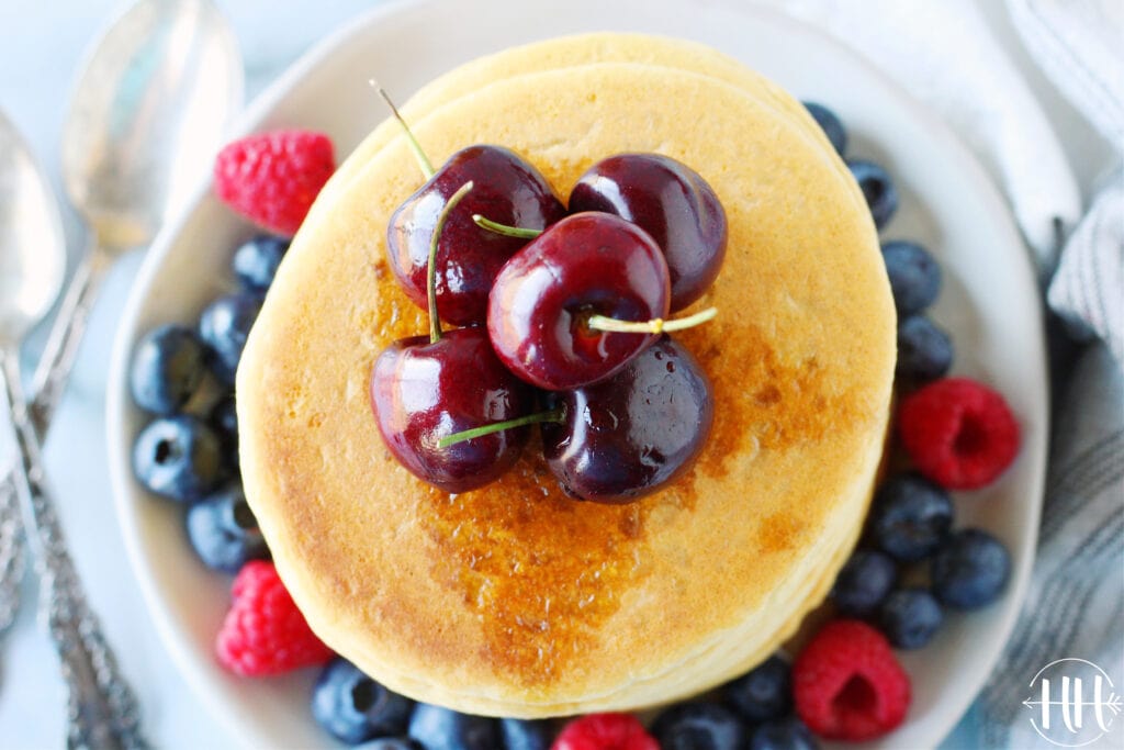 Bird's eye view of vegan protein pancakes topped with fresh cherries. 