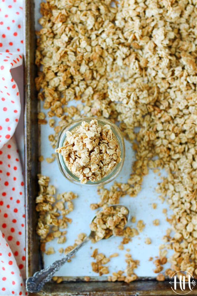 Birds eye view of a mason jar overflowing with French Toast Granola on the sheet pan of the fresh recipe.