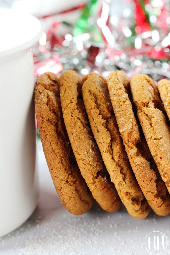 Chewy and soft deep brown cookies stacked against a mug. 