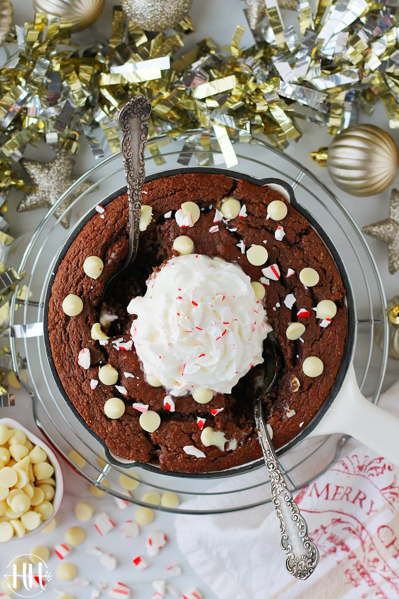 Overhead photo of small Christmas cake topped with candy cane and white chocolate chips.