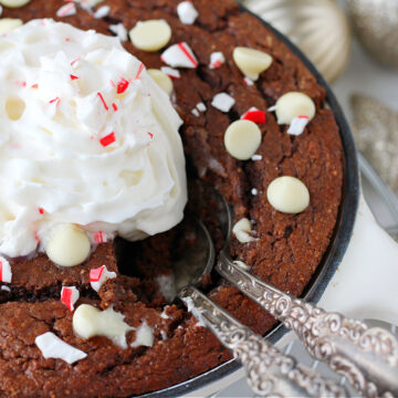 Two spoons in a chocolate protein cake topped with whipped cream.