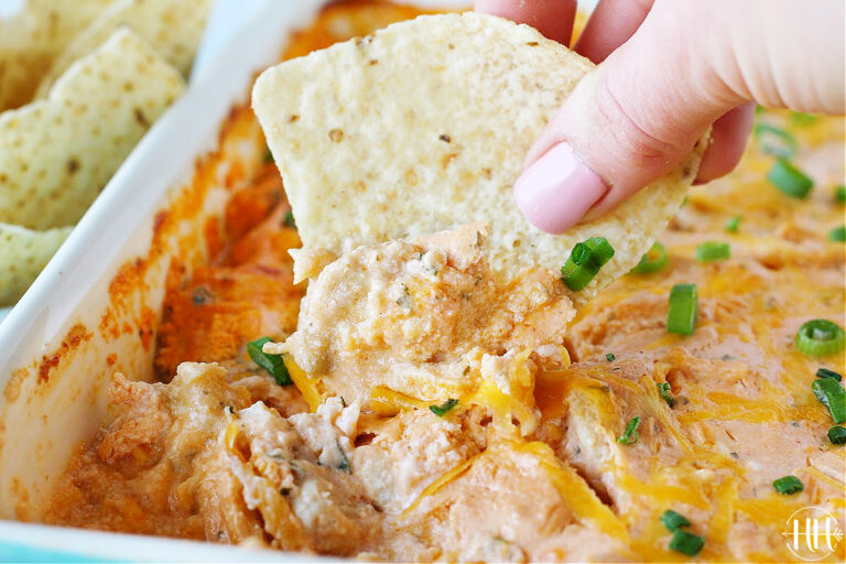 Up close photo of a tortilla chip dipped into a pan of buffalo chicken dip.