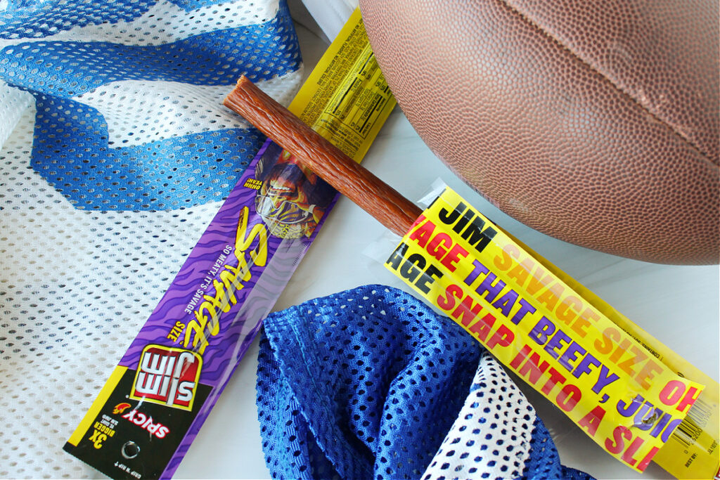 Slim Jim Savage Spicy sticks are beefy and yummy alongside a football and jersey.