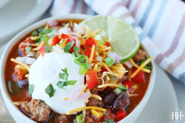 Up close photo of healthy taco soup with lime wedges, green onion, and Greek yogurt.