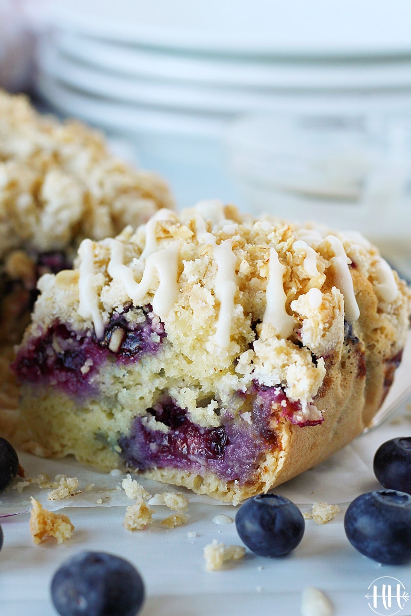 A slice of blueberry coffee cake with crumble topping drizzled with a glaze.