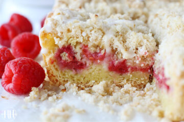 Up close photo of layered raspberry coffee cake drizzled with a powdered sugar glaze.