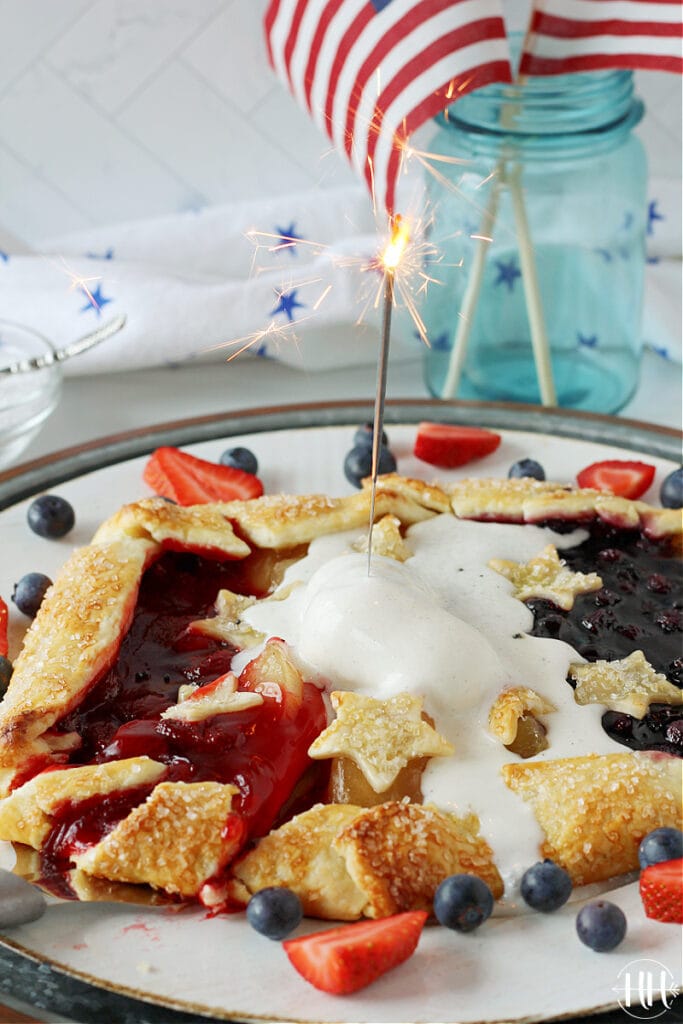 A 4th of July sparkler on top of a red white and blue galette. 