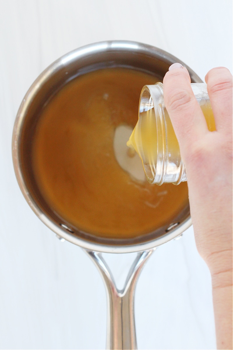 Chicken bone broth being poured into a small soup pot.