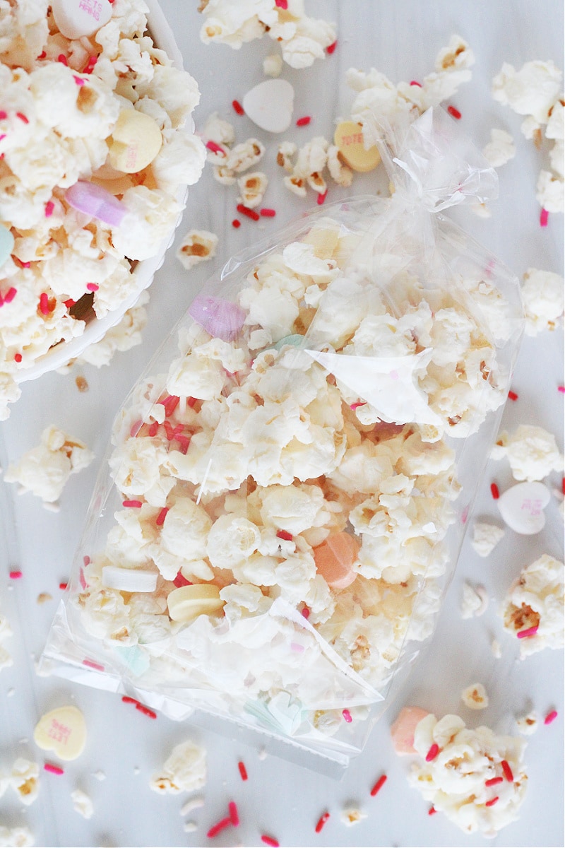 White Chocolate Valentine's Popcorn with conversation hearts and sprinkles in clear gift bags.