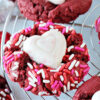 Photo of a red velvet cookie with Valentine sprinkles and a white chocolate heart.