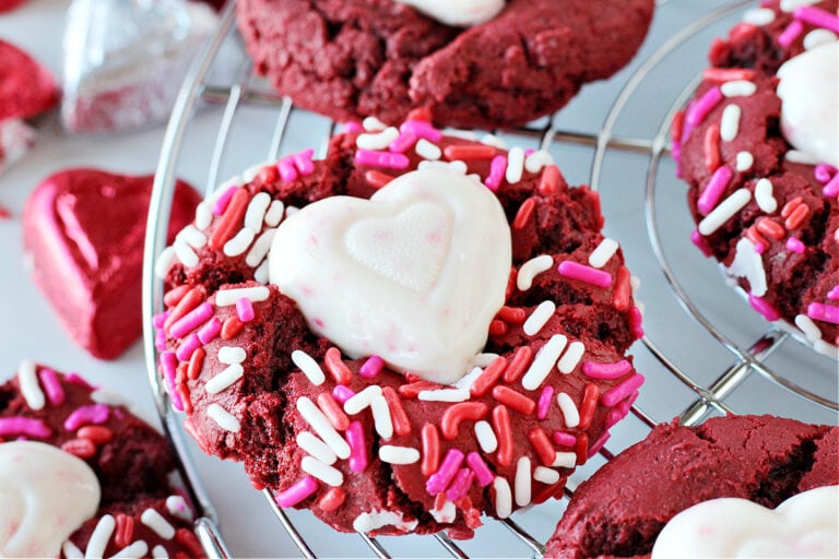 Photo of a red velvet cookie with Valentine sprinkles and a white chocolate heart.