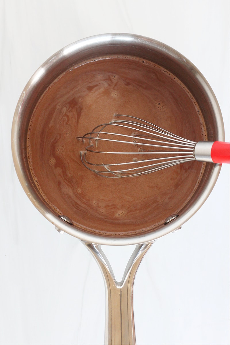 Whisk stirring high protein bone broth hot cocoa in a small soup pot.
