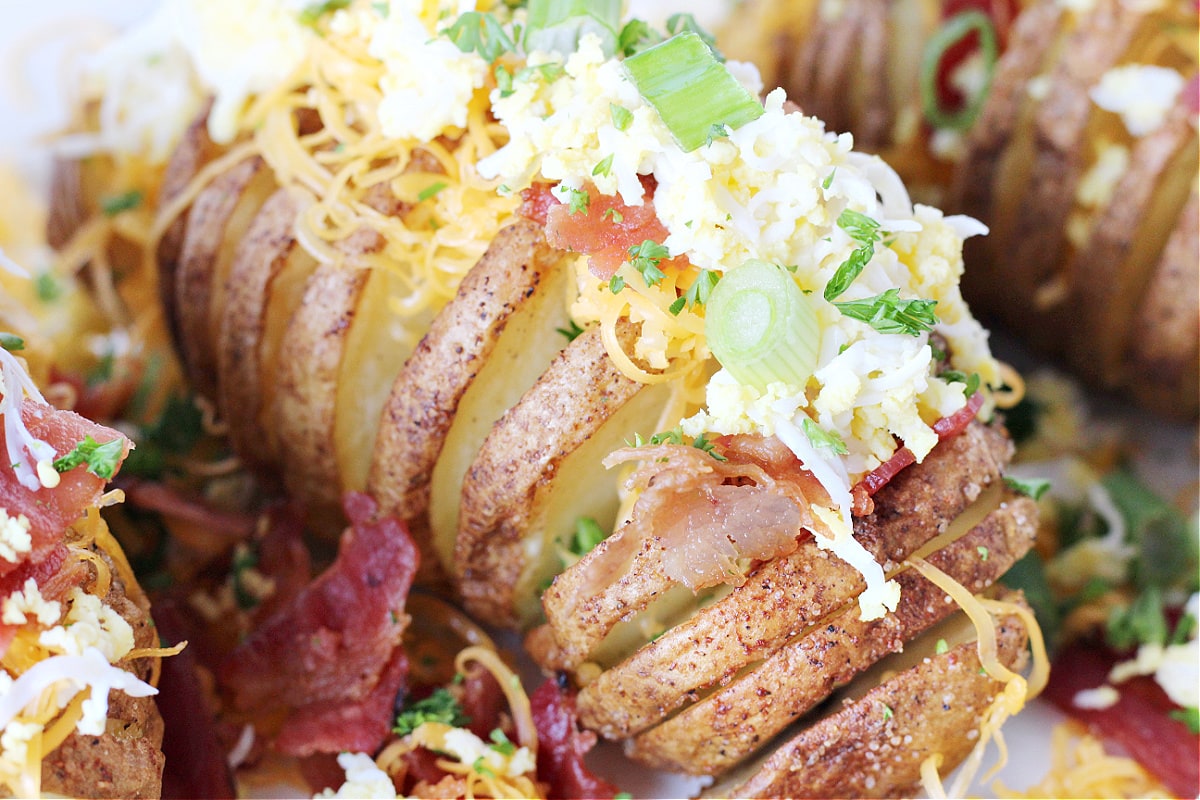 Up close photo of a breakfast air fryer hasselback potato with bacon and egg toppings.