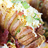 Green onion, shredded cheese, grated egg, and bacon topping a hasselback potato.