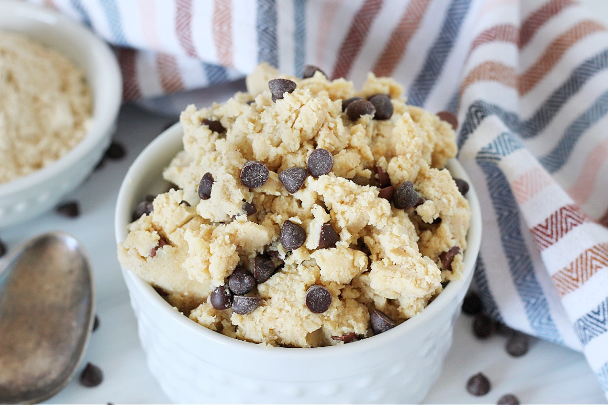 Edible cookie dough studded with chocolate chips in a white bowl.