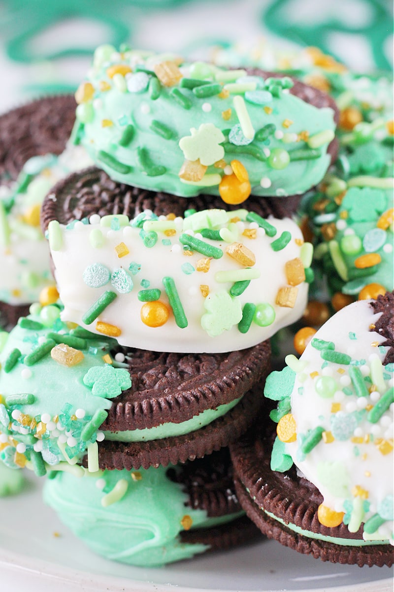 St. Patrick's Day White Chocolate Dipped Oreos with sprinkles stacked high on a plate.