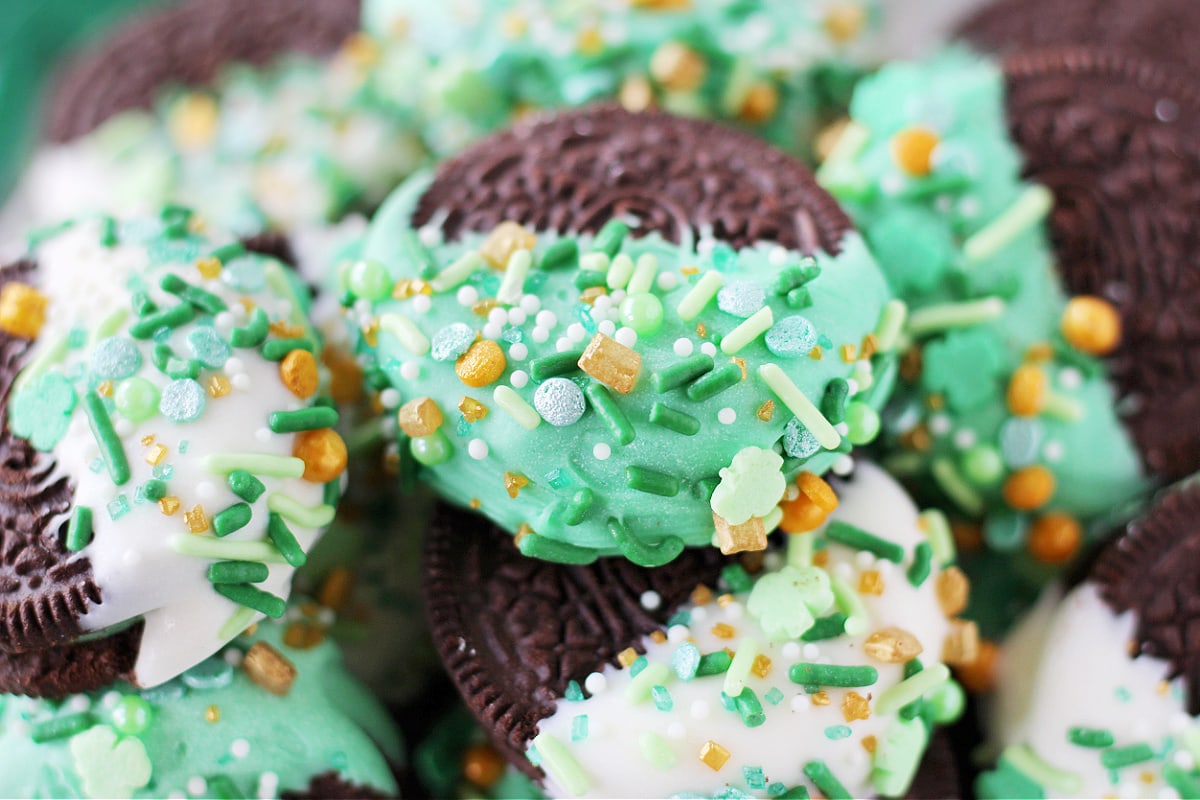 Up close photo of a green chocolate dipped Oreo cookie with St. Patrick's sprinkles.