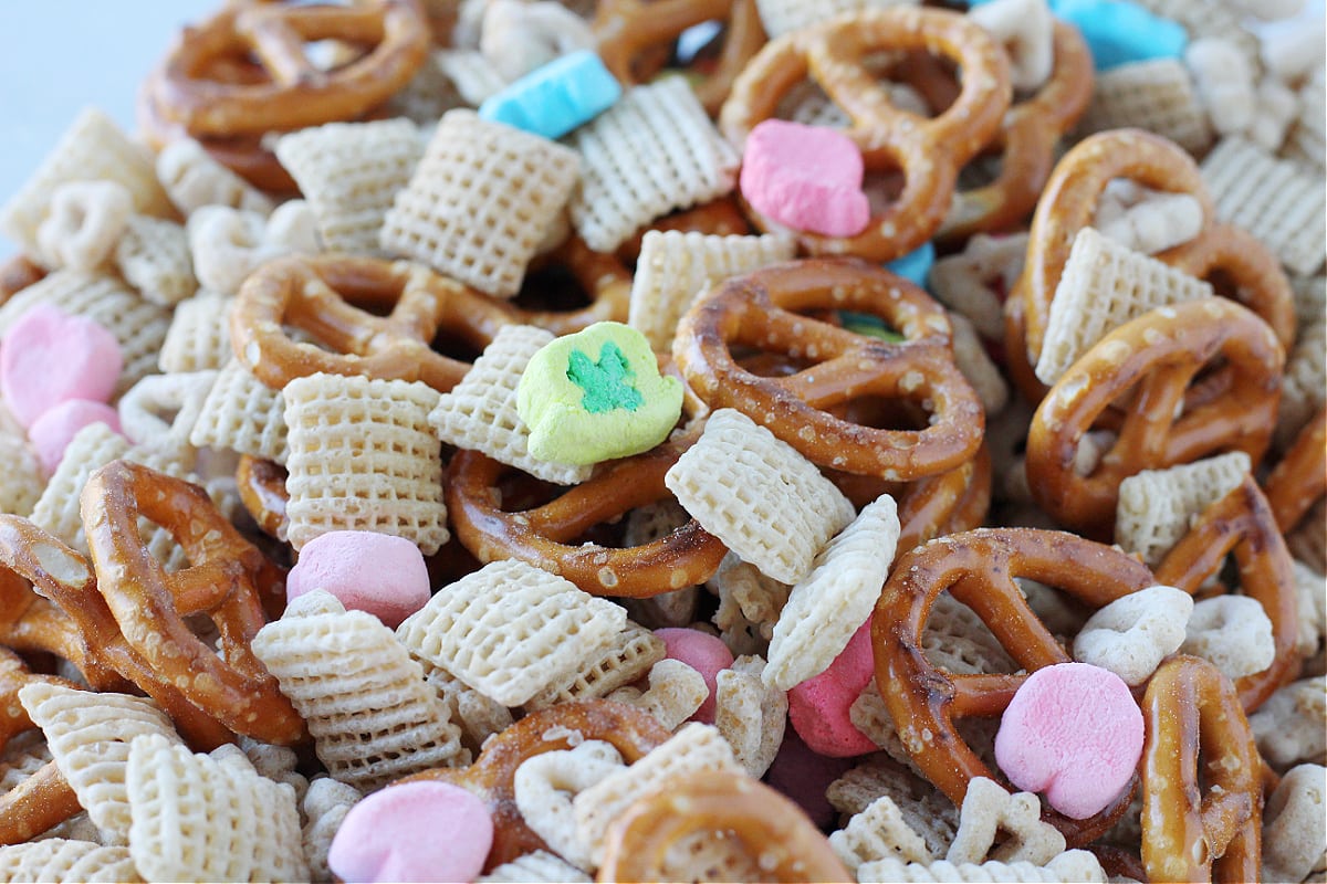 Up close photo of twisty pretzels, rice Chex cereal, and Lucky Charms cereal mixed together.