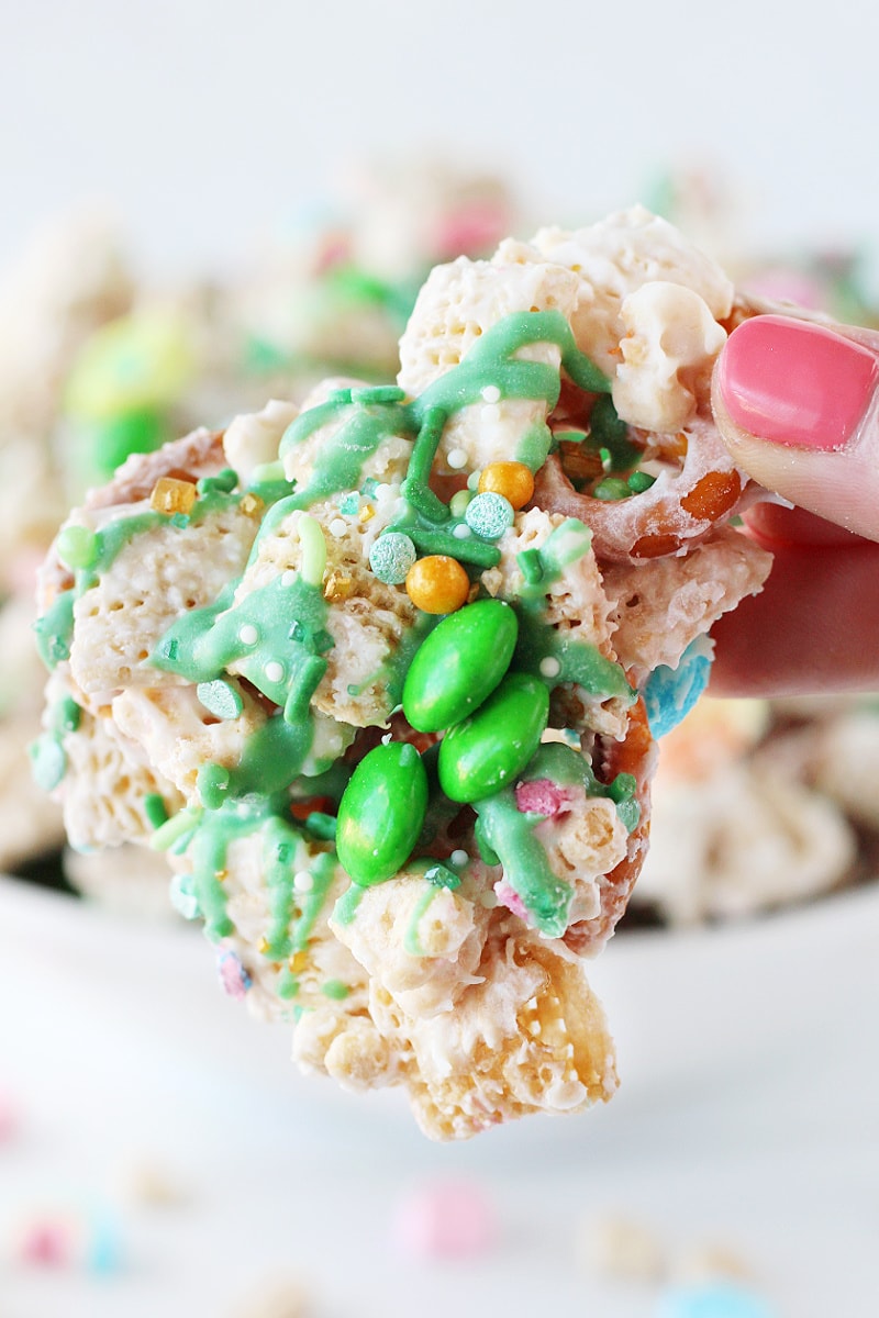 A woman's fingers holding leprechaun bait with green M&Ms and St. Patrick's Day sprinkles.