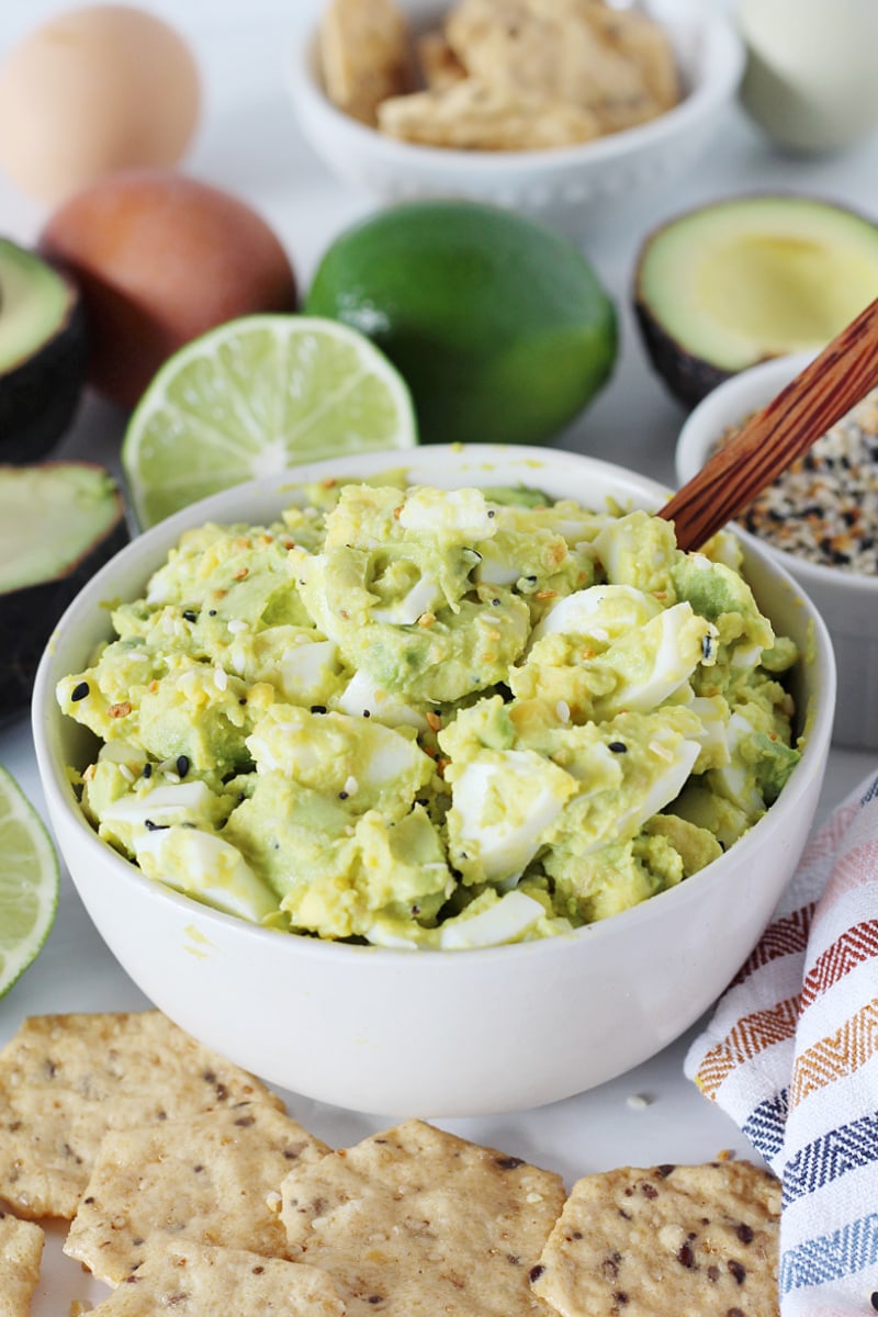 4 Ingredient Avocado Egg Salad in a white bowl with a wooden spoon in it. 