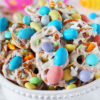 Easter Pretzel Bark in a white bowl with pastel chocolate Robin Eggs candies.