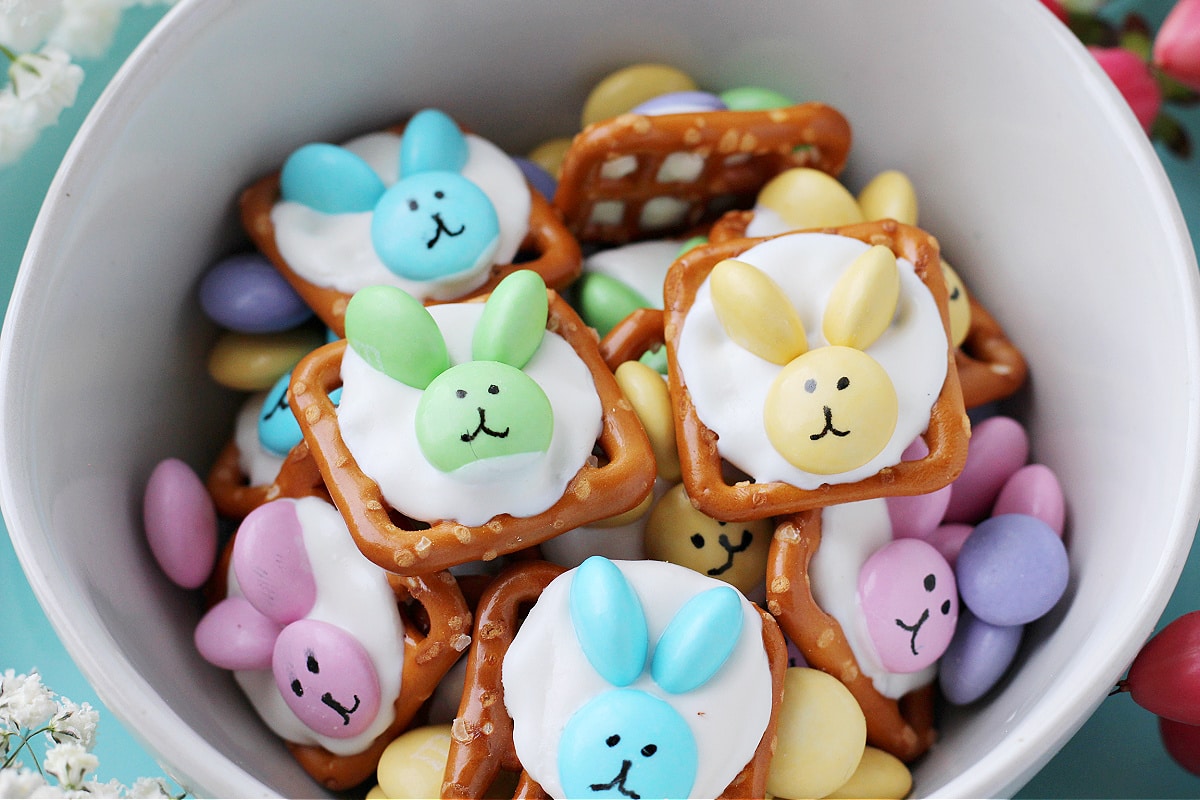 Cute Easter Bunny Pretzels made with white chocolate melts and pastel M&Ms in a bowl.