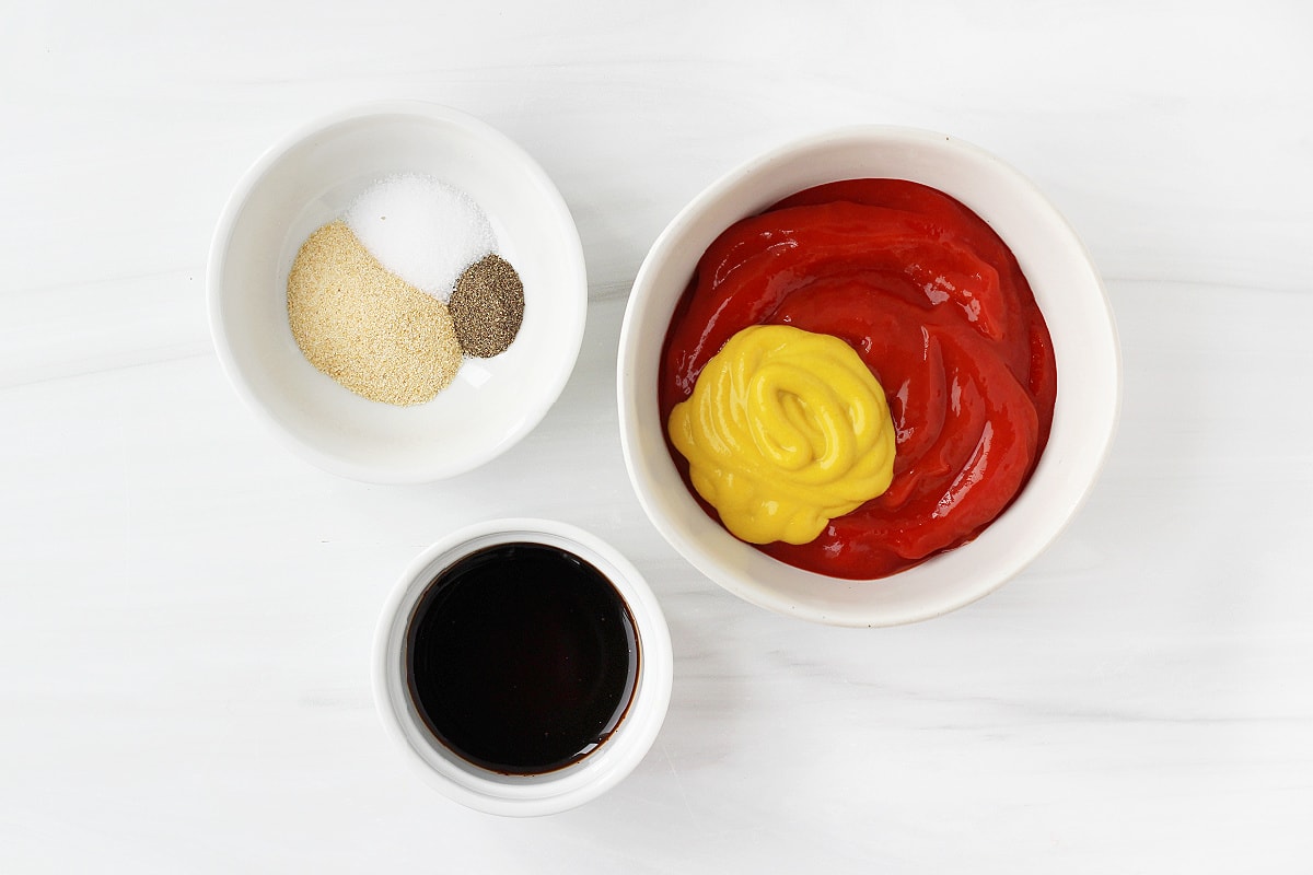 Three bowls each filled with ketchup and mustard, Worcestershire sauce and seasonings.