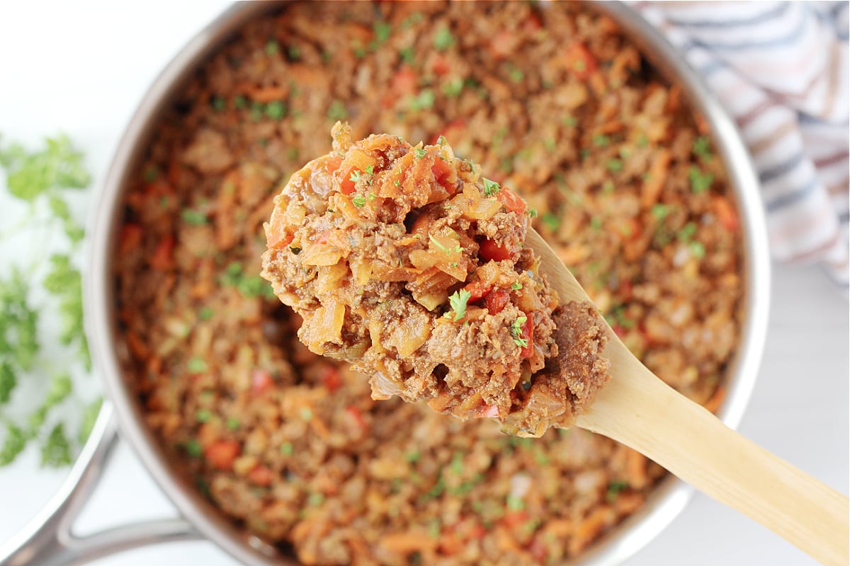 Overhead photo of a wooden spoon with healthy sloppy joes on it over the pan.