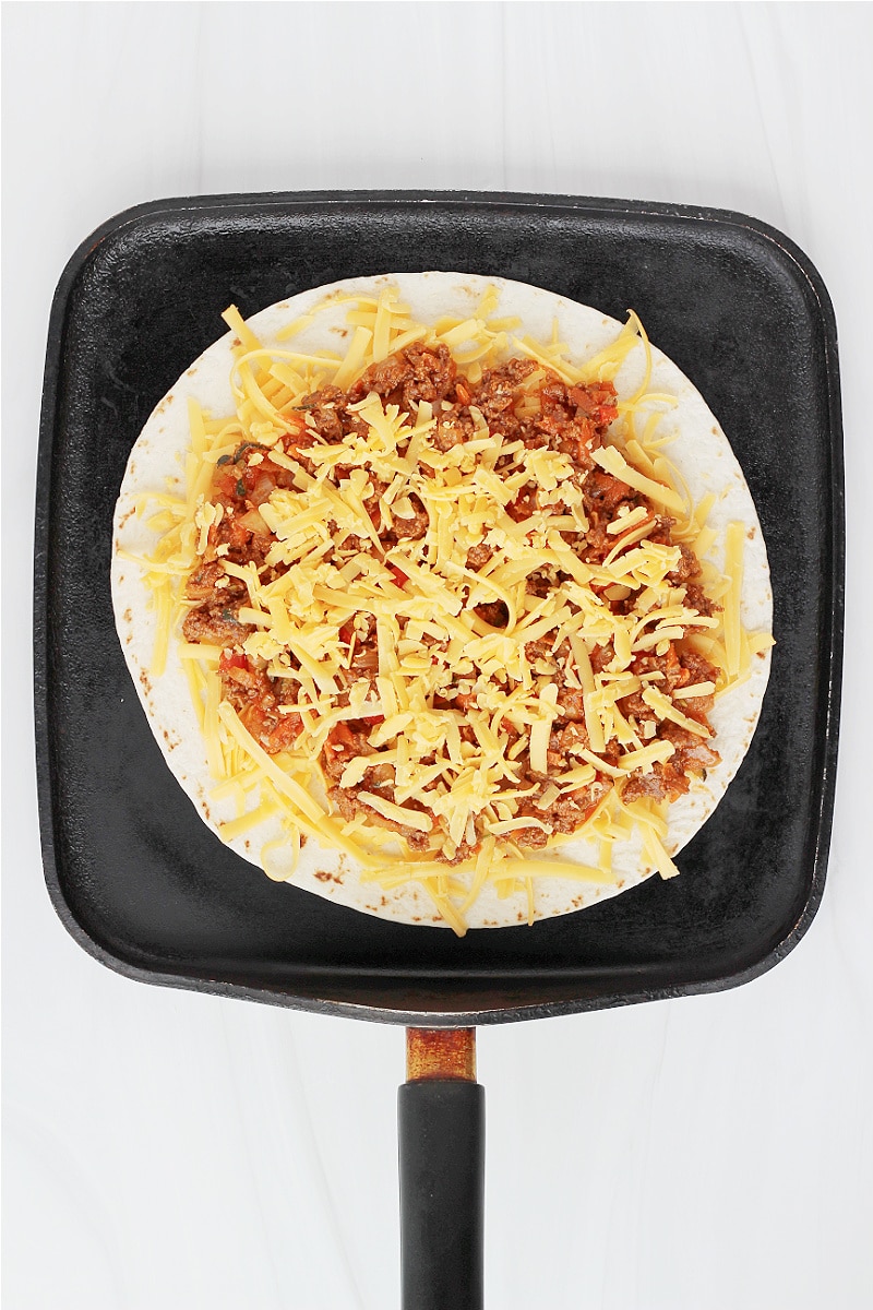 Overhead photo of an open faced sloppy joe quesadilla on a flat pan.