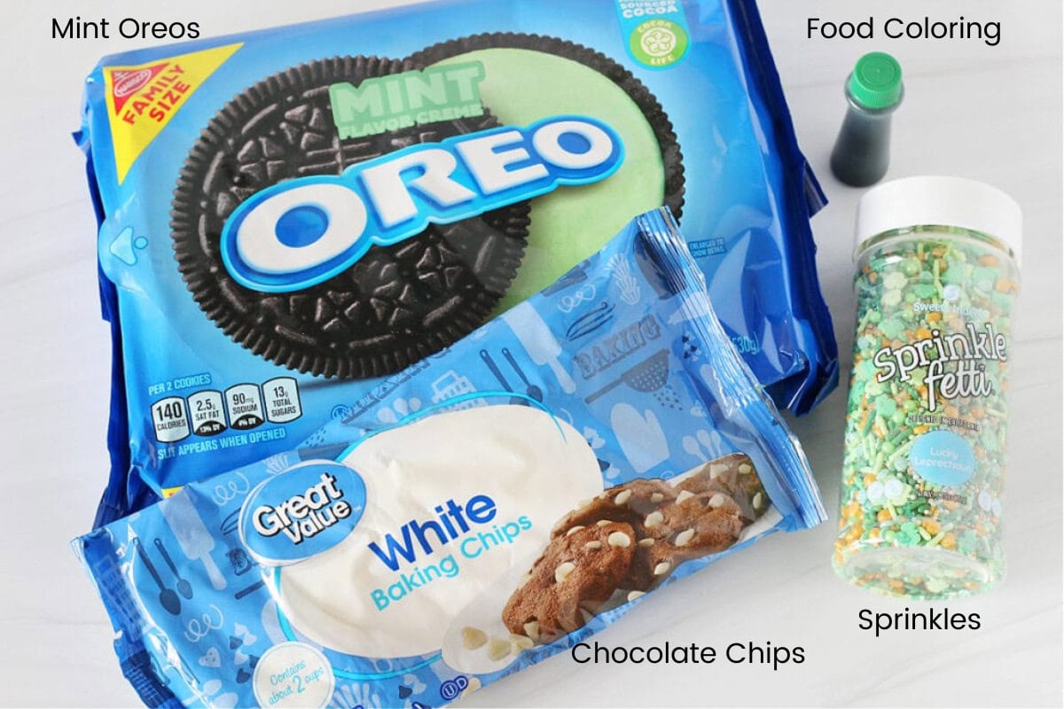 Labeled ingredients for St. Patrick's Day White Chocolate Dipped Oreos on a white marble countertop.