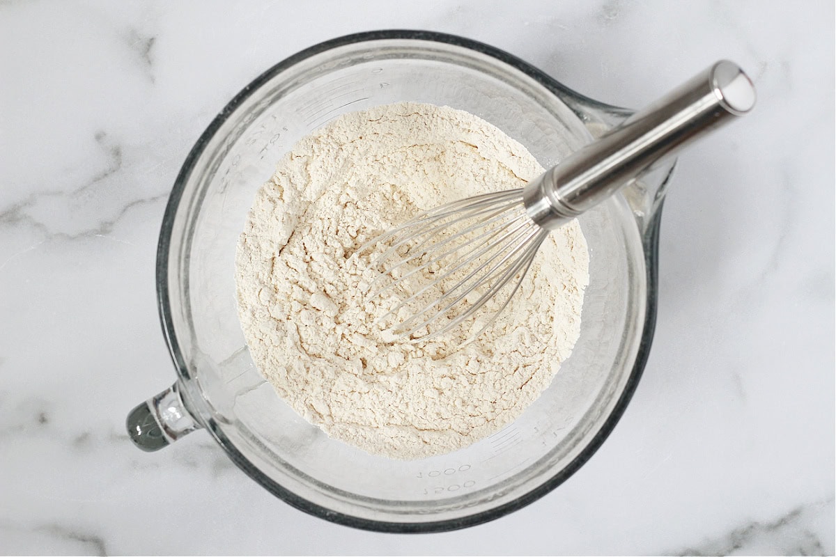 Flour, baking soda and cinnamon whisked together in a glass mixing bowl.