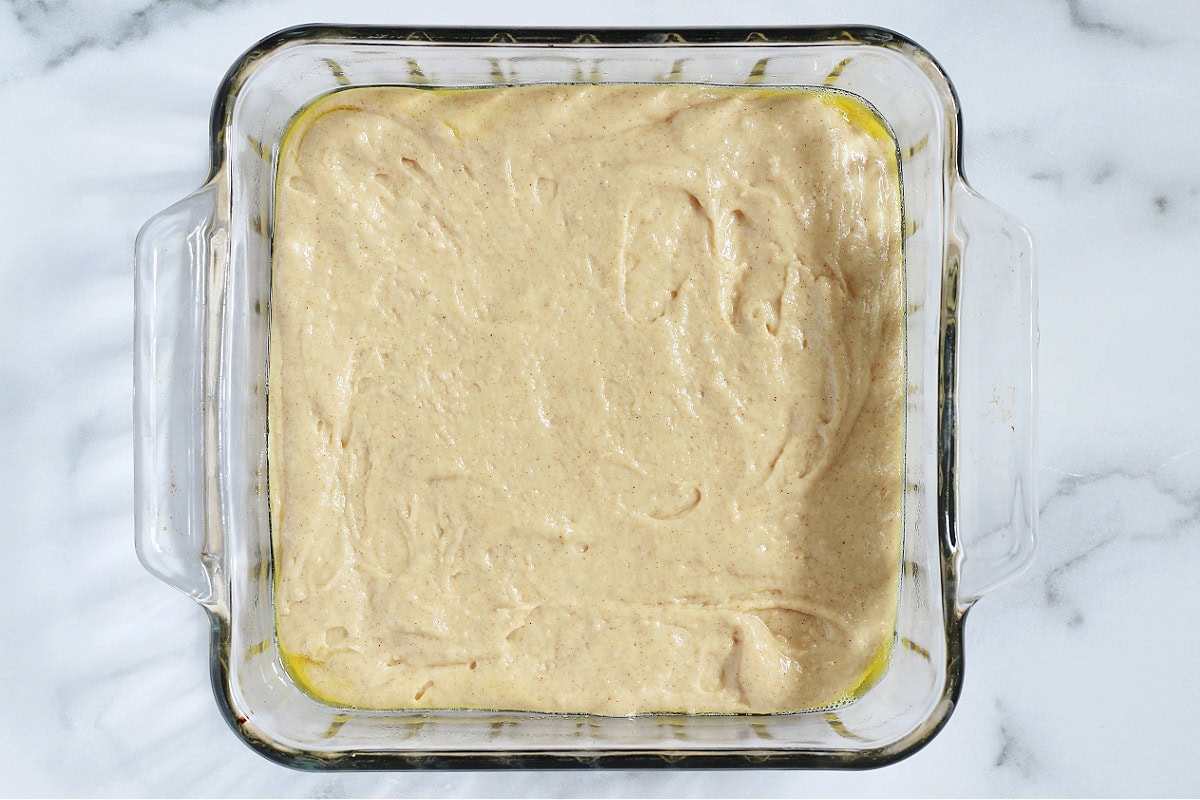 A coffee cake batter in a greased 8x8 glass pan.