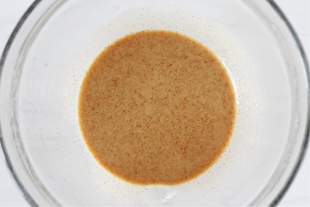 Overhead photo of almond butter, honey, and coconut oil mixed together in a glass bowl.