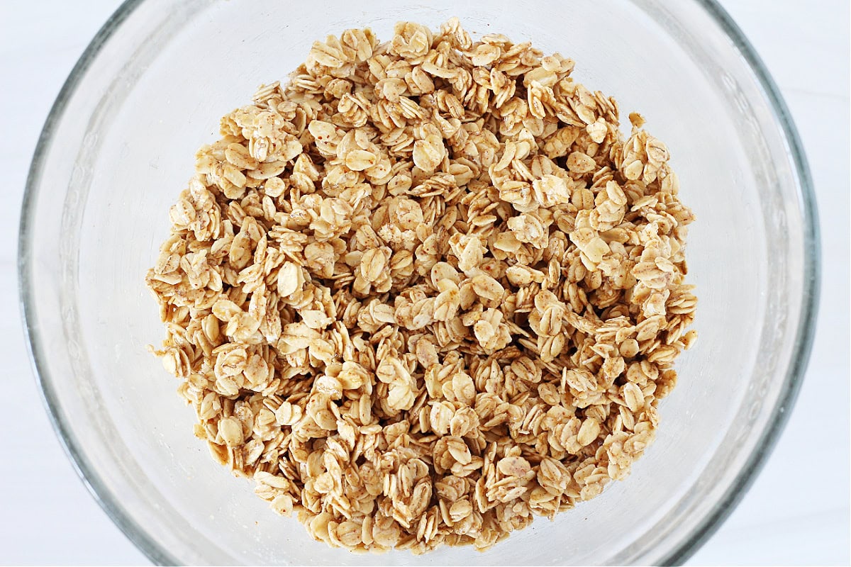 Overhead photo of oats mixed with honey and almond butter in a glass bowl.