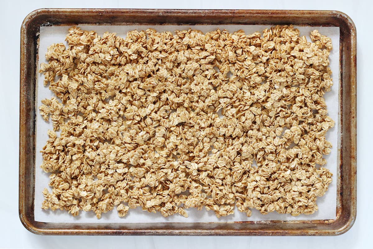 A baking pan with parchment paper covered with unbaked granola.