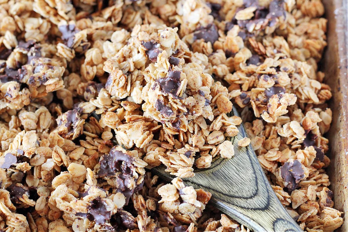 Up close photo of salted dark chocolate granola on a black wooden spoon.