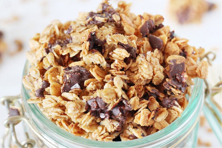 Up close photo of salted dark chocolate granola overflowing a glass jar.