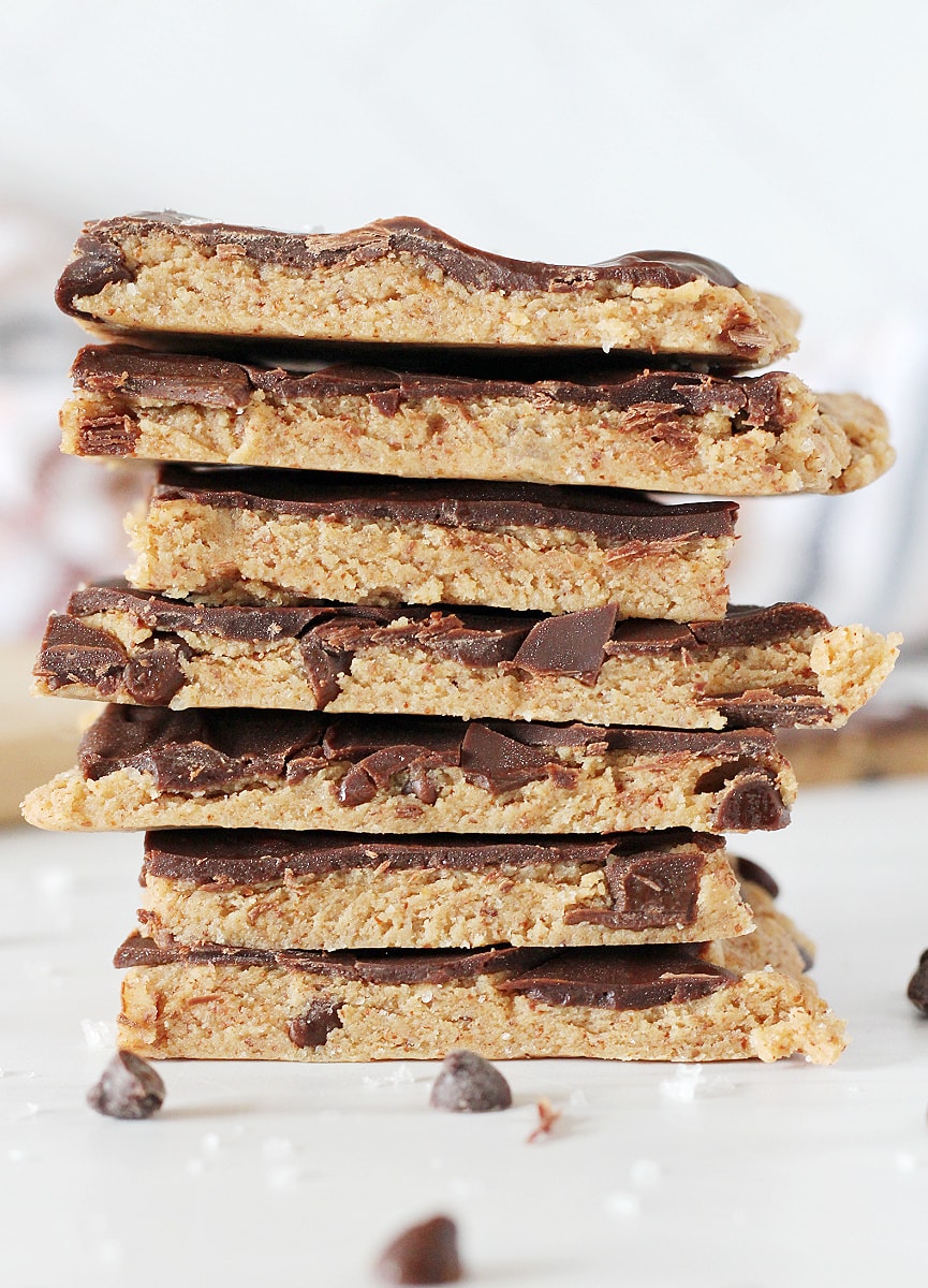 Seven pieces of high protein cookie dough bark stacked on a white countertop.