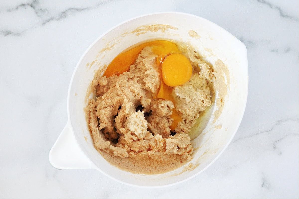 Two farm fresh eggs in a mixing bowl with wet ingredients for cookies.