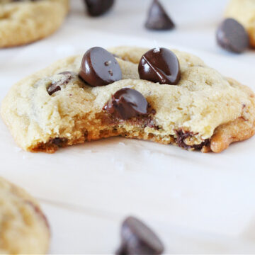 Up close photo of a cookie topped with chocolate chips and a bite taken out.