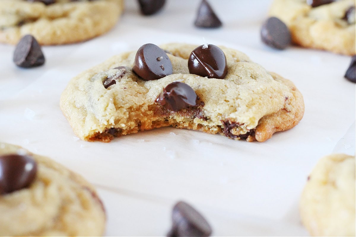 Up close photo of a cookie topped with chocolate chips and a bite taken out.