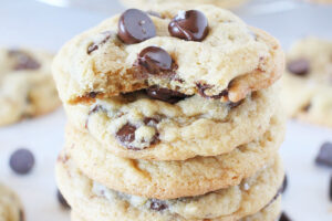A stack of chocolate chip cookies with a bite taken out of the top cookie.