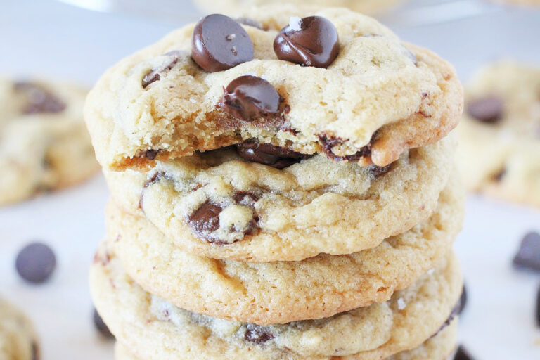 A stack of chocolate chip cookies with a bite taken out of the top cookie.